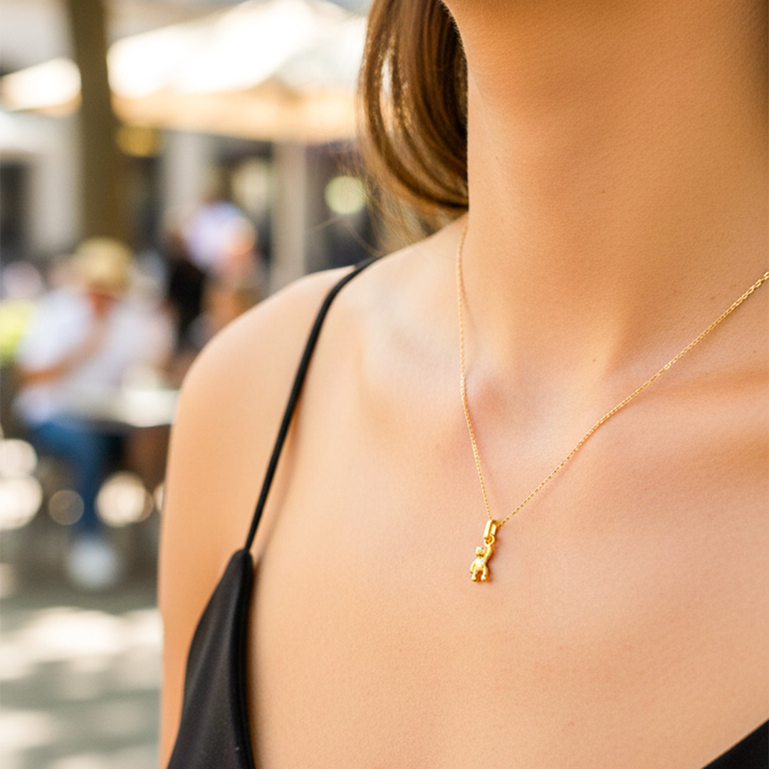 Cuello de modelo usando una cadena con un dije en forma de osito Teddy en oro amarillo de 18 quilates de Joyería Caracas.