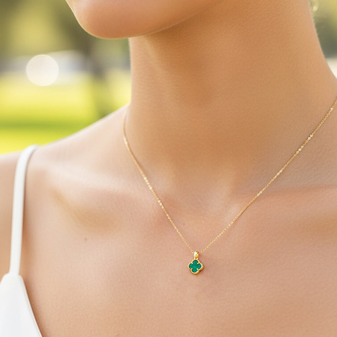 Cuello de modelo usando una cadena con un dije en forma de trébol en oro amarillo de 18 quilates con marmoleado en color verde de Joyería Caracas.