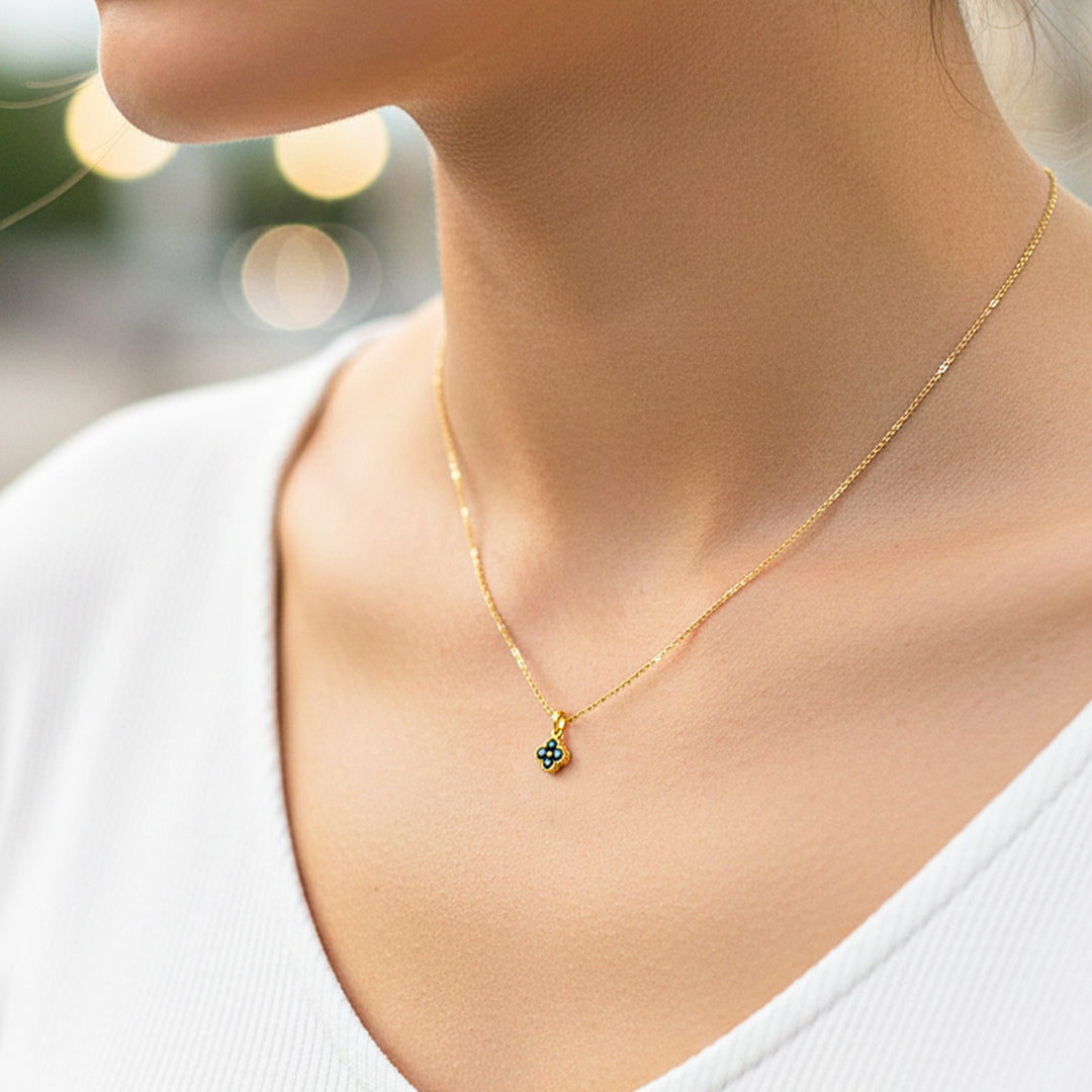 Cuello de modelo usando una cadena con un dije en forma de trébol en oro amarillo de 18 quilates con cristales negros de Joyería Caracas.