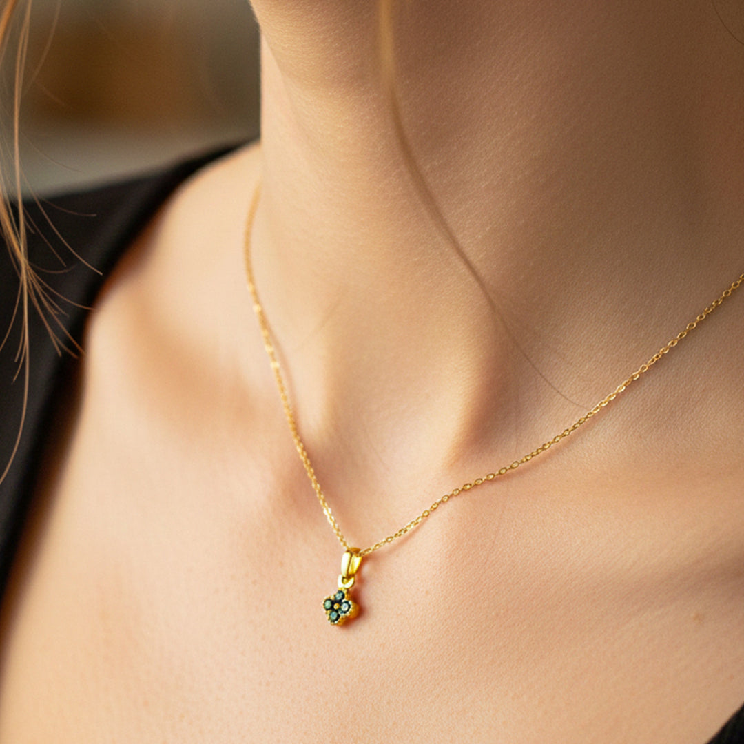 Cuello de modelo usando una cadena con un dije de trébol en oro amarillo de 18 quilates con cristales negros de Joyería Caracas.