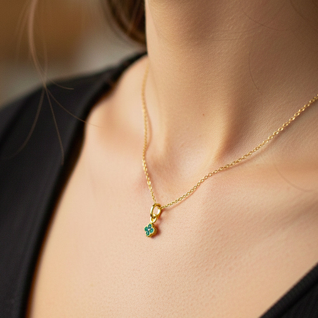 Cuello de modelo usando una cadena con un dije de trébol en oro amarillo de 18 quilates con cristales verdes de Joyería Caracas.
