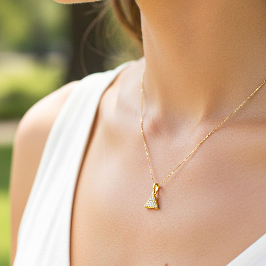 Cuello de modelo usando una cadena con un dije en forma de triángulo en oro amarillo de 18 quilates con cristales de Joyería Caracas.