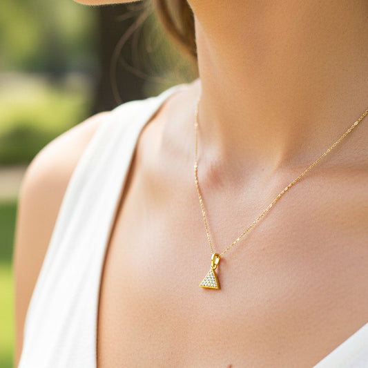 Cuello de modelo usando una cadena con un dije en forma de triángulo en oro amarillo de 18 quilates con cristales de Joyería Caracas.