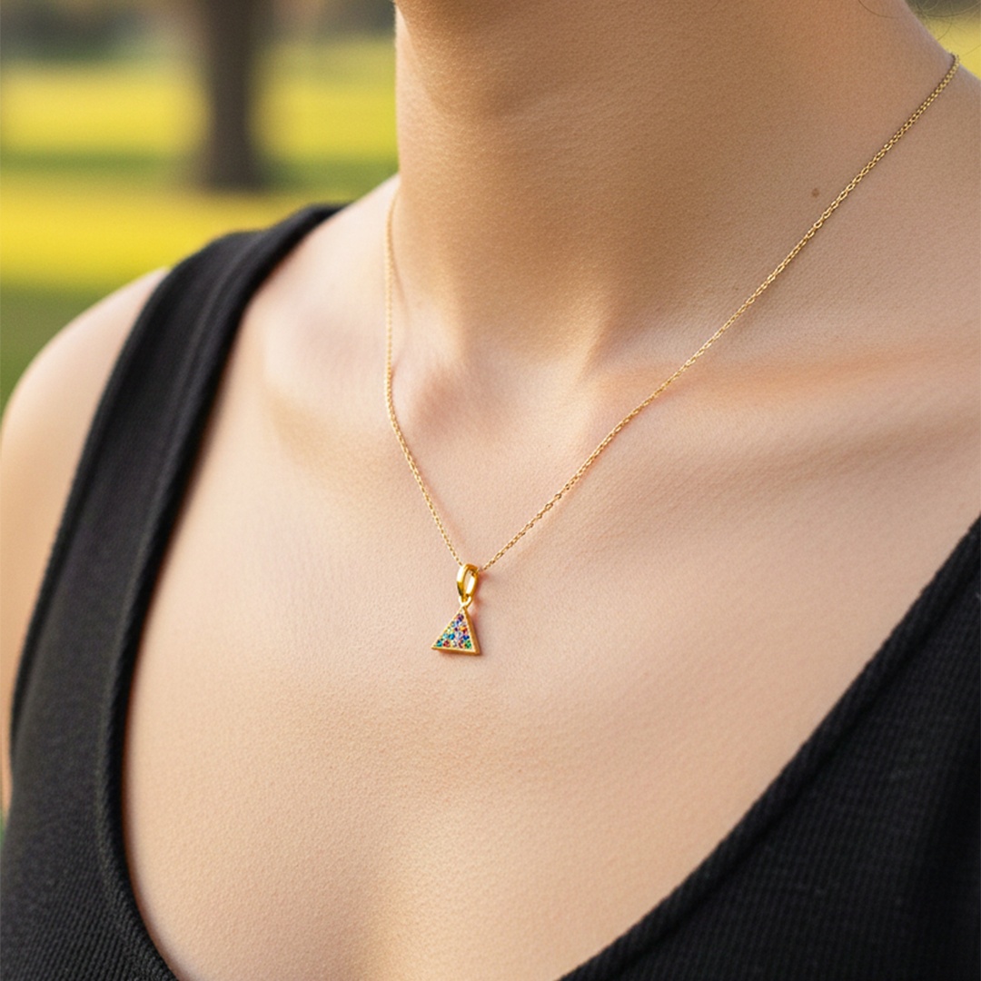 Cuello de modelo usando una cadena con un dije en forma de triángulo en oro amarillo de 18 quilates con cristales multicolor de Joyería Caracas.