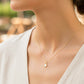 Cuello de modelo usando una cadena con dije en forma de tulipán en oro amarillo de 18 quilates con Nacar blanco de Joyería Caracas. 