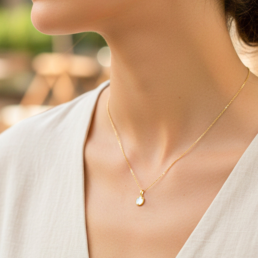 Cuello de modelo usando una cadena con dije en forma de tulipán en oro amarillo de 18 quilates con Nacar blanco de Joyería Caracas. 