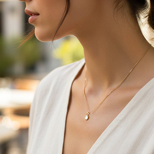 Cuello de modelo usando una cadena con dije en forma de tulipán en oro amarillo de 18 quilates con Nacar blanco de Joyería Caracas. 