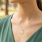 Cuello de modelo usando una cadena con un dije en forma de placa en forma de nube de la Virgen María en oro amarillo de 18 quilates de Joyería Caracas.