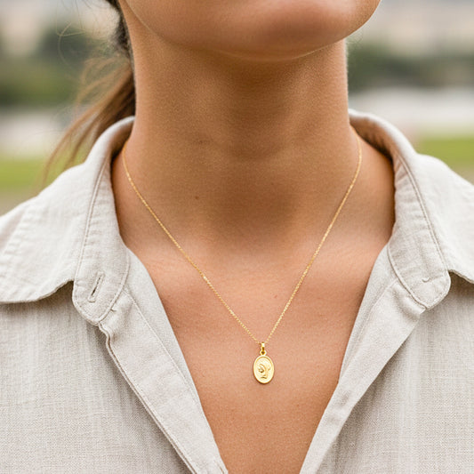 Cuello de modelo usando una cadena con un dije en forma de placa ovalada de la Virgen María en oro amarillo de 18 quilates de Joyería Caracas.