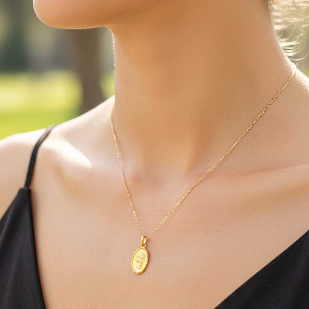 Cuello de modelo usando una cadena con un dije en forma de placa ovalada diamantada de la Virgen María en oro amarillo de 18 quilates de Joyería Caracas.