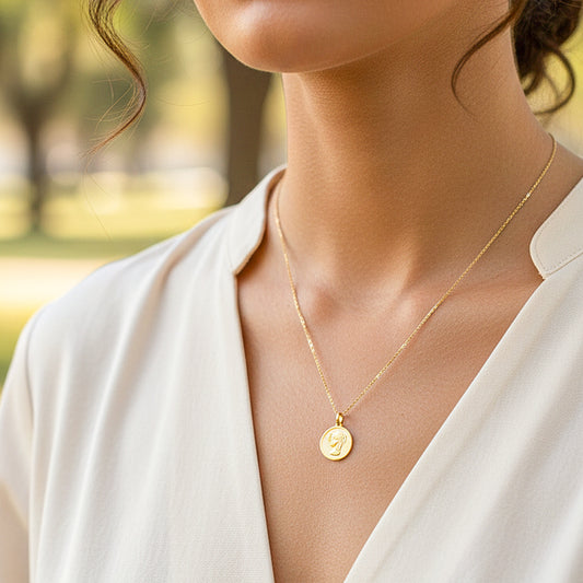 Cuello de modelo usando una cadena con un dije de la placa de la Virgen María redonda en oro amarillo de 18 quilates de Joyería Caracas.