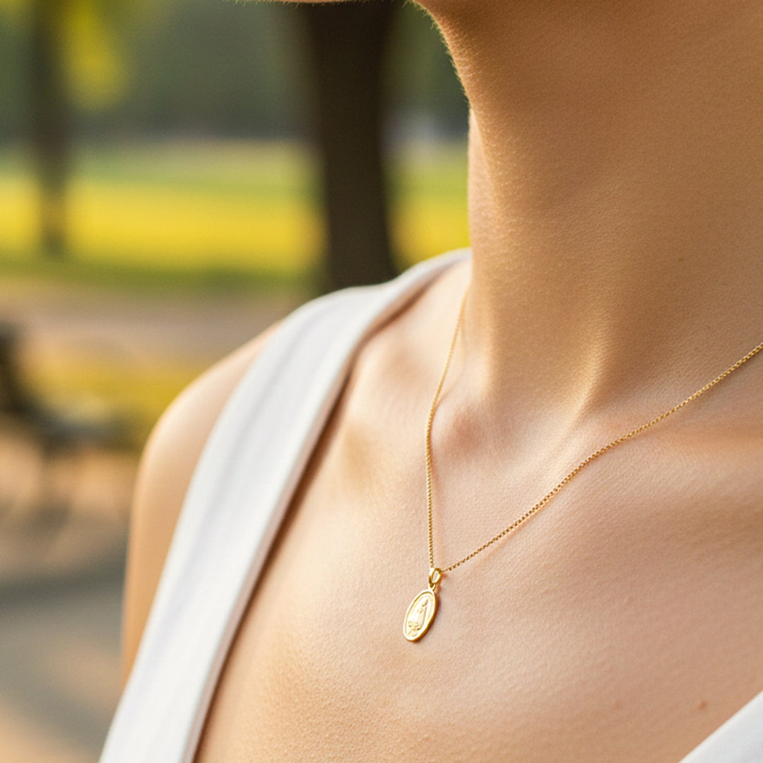 Cuello de modelo usando una cadena con un dije ovalado de la Virgen de la Caridad en oro amarillo de 18 quilates de Joyería Caracas.