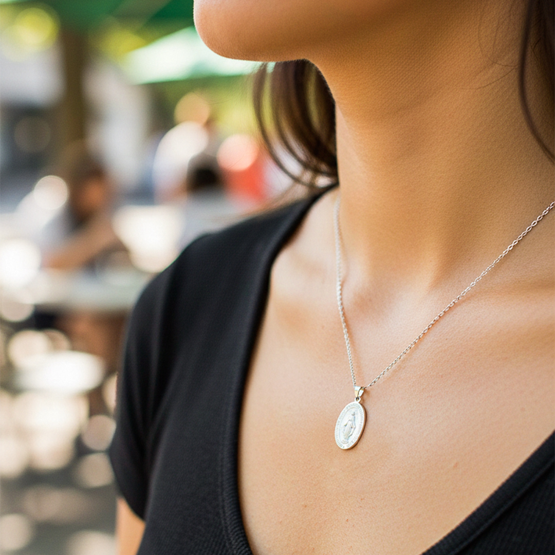 Cuello de modelo usando una cadena con un dije en forma de la Virgen Milagrosa en oro blanco de 18 quilates de Joyería Caracas.