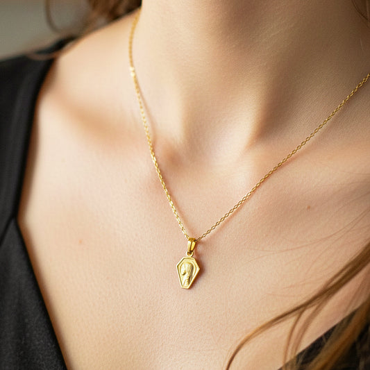 Cuello de modelo usando una cadena con un dije en forma de la Virgen en oro amarillo de 18 quilates de Joyería Caracas.