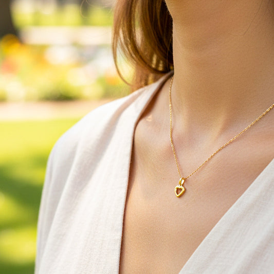 Cuello de modelo usando una cadena con un dije en forma de la silueta de corazón en oro amarillo de 18 quilates de Joyería Caracas.