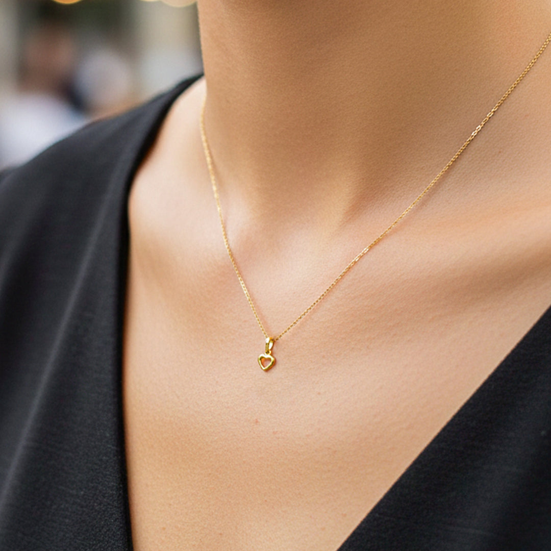 Cuello de modelo usando una cadena con un dije en forma de silueta de corazón en oro amarillo de 18 quilates de Joyería Caracas.
