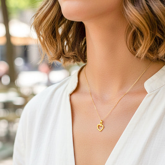 Cuello de modelo usando una cadena con un dije en forma de corazón diamantado en oro amarillo de 18 quilates de Joyería Caracas.