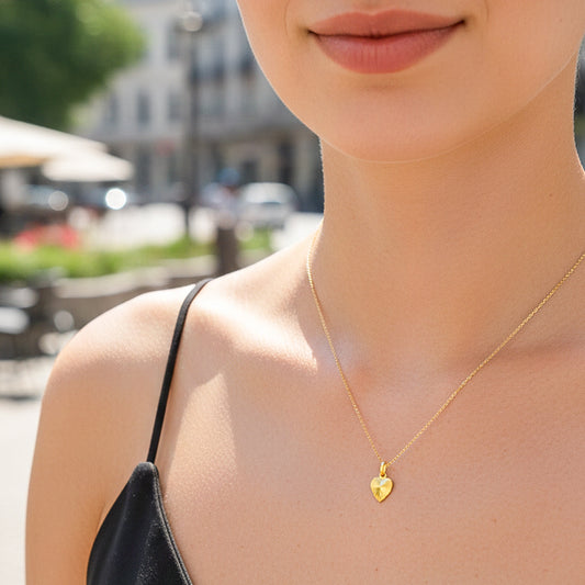 Cuello de modelo usando una cadena con un dije en forma de corazón diamantado en oro amarillo de 18 quilates de Joyería Caracas.