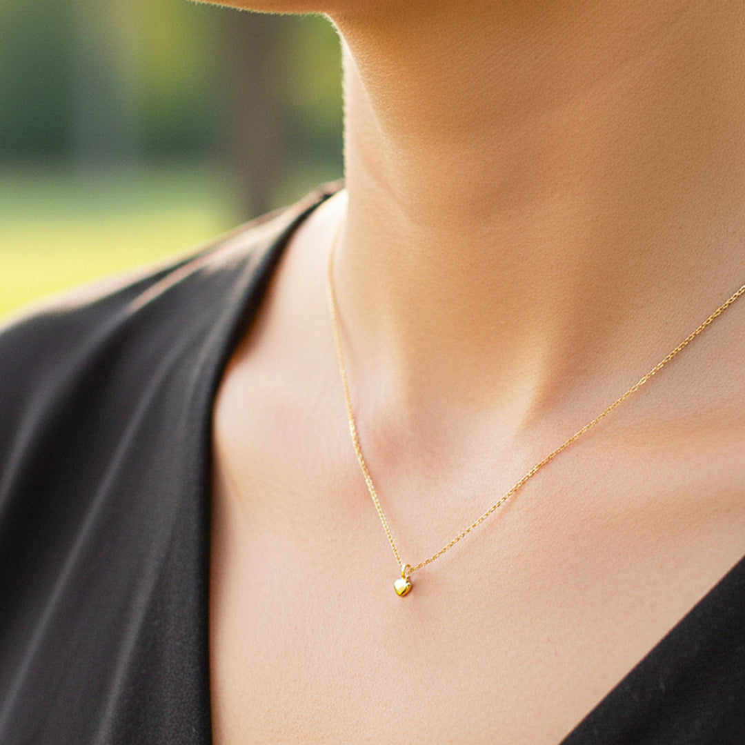 Cuello de modelo usando una cadena con un dije en forma de corazón en oro amarillo de 18 quilates de Joyería Caracas.