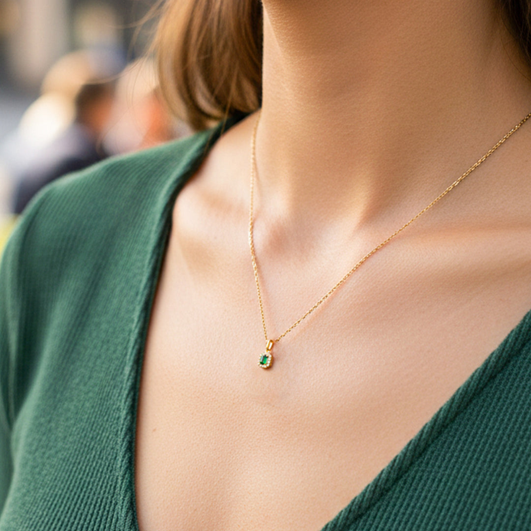 Cuello de modelo usando una cadena con un dije rectangular en oro amarillo de 18 quilates con Esmeralda de Joyería Caracas.