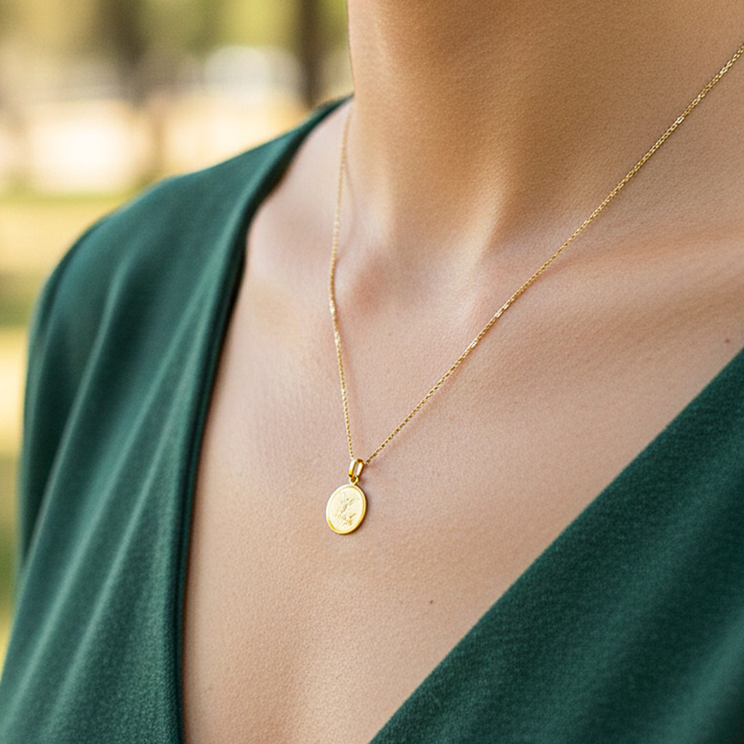 Cuello de modelo usando una cadena con un dije en forma de placa fotograbada de San Miguel en oro amarillo de 18 quilates de Joyería Caracas.