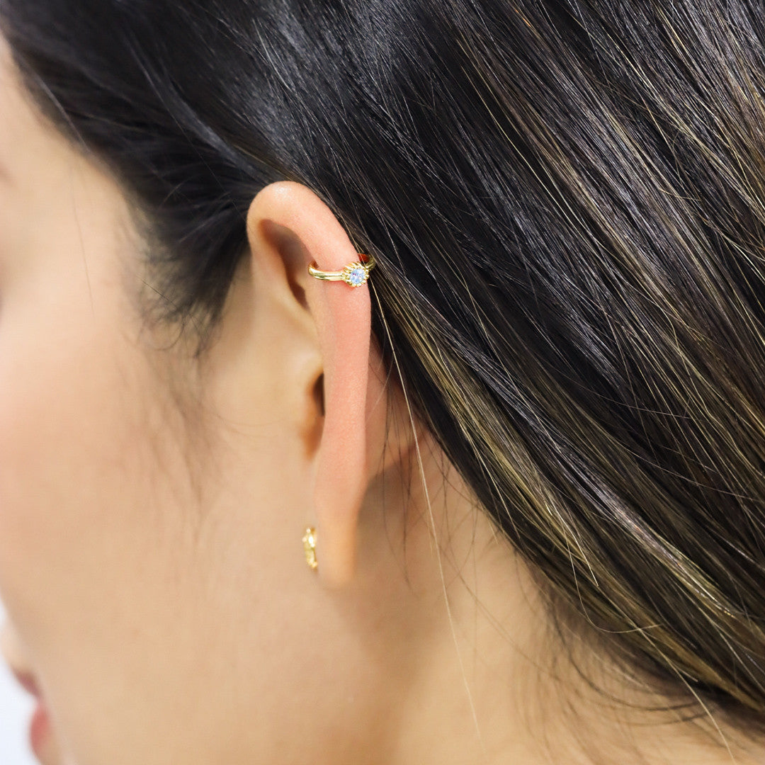 Oreja de mujer con earcuff en oro amarillo de 18 quilates y cristal de color blanco, hecho en Joyería Caracas. 