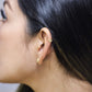 Oreja de mujer con earcuff en forma de tréboles en oro amarillo de 18 quilates con cristales de color blanco, hecho en Joyería Caracas. 