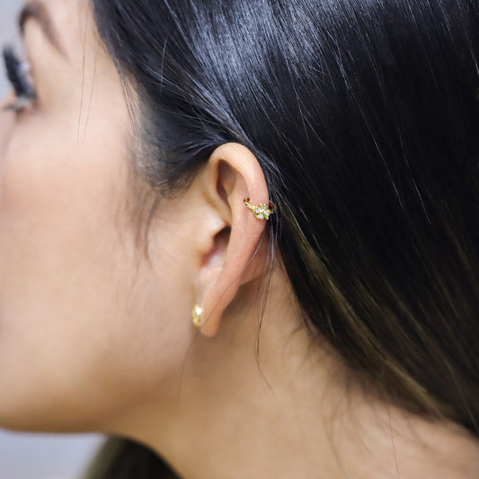 Oreja de mujer con earcuff en forma de tréboles en oro amarillo de 18 quilates con cristales de color blanco, hecho en Joyería Caracas. 