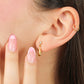 Oreja de mujer con topito en forma de gota en oro amarillo de 18 quilates con cristal de color verde, hechos en Joyería Caracas. 