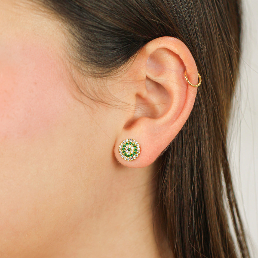 Oreja de mujer con topito en forma circular en oro amarillo de 18 quilates con cristales de color verde y blanco, hechos en Joyería Caracas. 