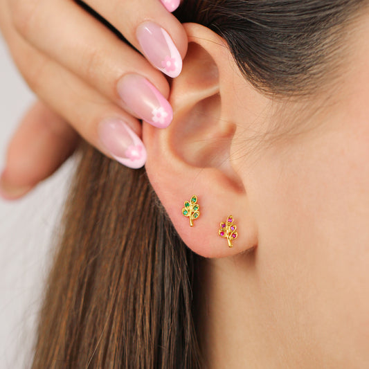 Oreja de mujer con topito en forma de racimo en oro amarillo de 18 quilates con 5 cristales de color rojos, hechos en Joyería Caracas. 