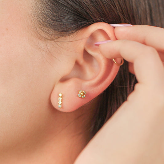 Oreja de mujer con topito en oro amarillo de 18 quilates con 3 cristales de color blanco y perla, hechos en Joyería Caracas. 
