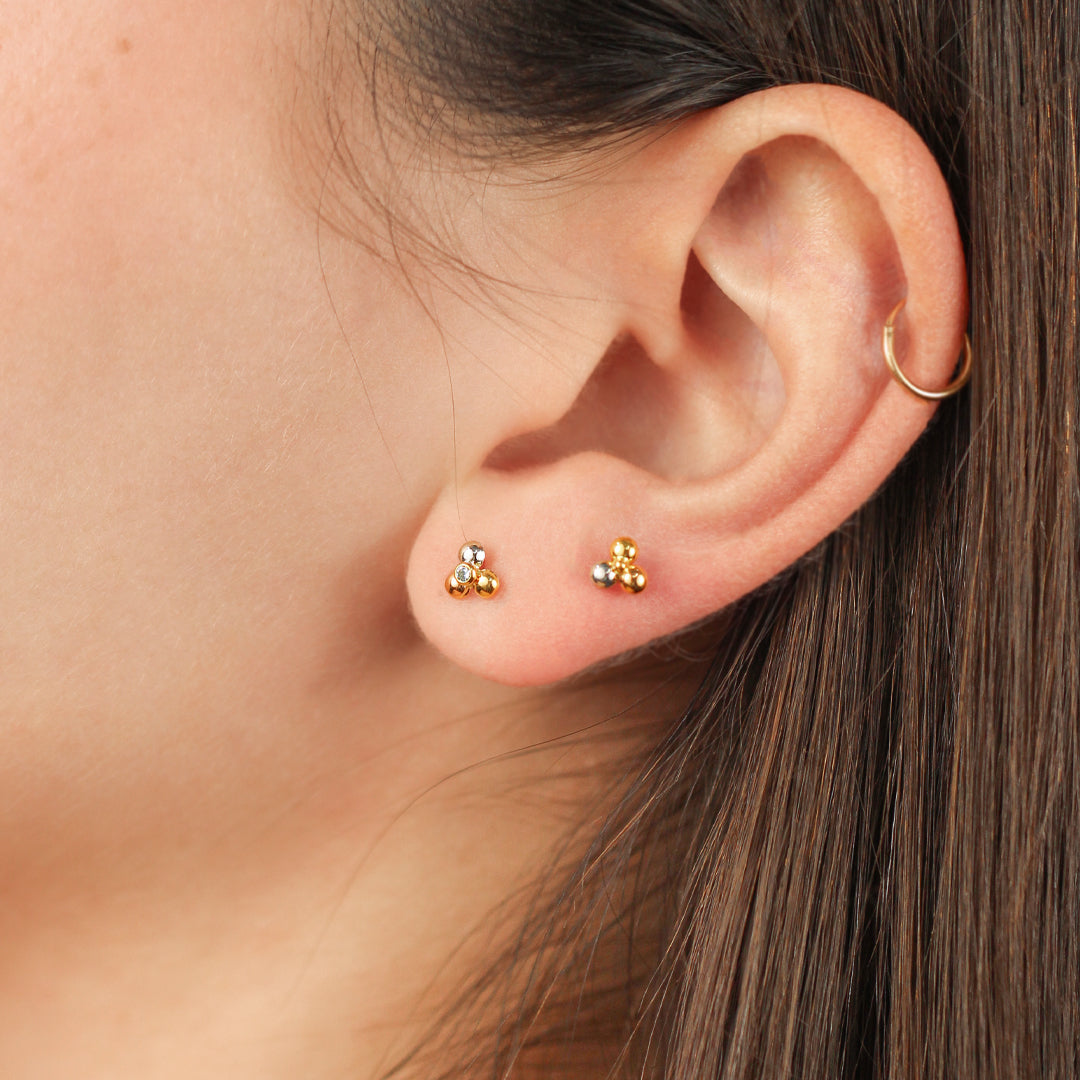 Oreja de mujer con topito en forma de flor de loto en oro blanco, rosa y amarillo de 18 quilates con cristal de color blanco en el centro, hechos en Joyería Caracas.