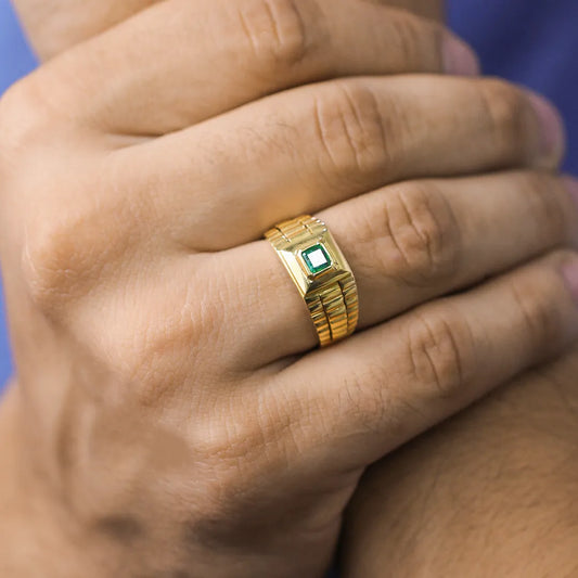 Mano de hombre con anillo Armis en oro amarillo de 18 quilates con esmeralda de color verde en el centro, hecho en Joyería Caracas. 
