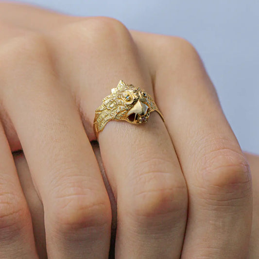 Mano de hombre con anillo en forma de águila en oro amarillo de 18k, con 2 cristales de color verde en los ojos y 1 cristal blanco en la punta del pico, hecho en Joyería Caracas. 