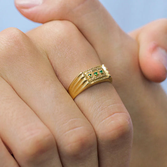 Mano de hombre con anillo en oro amarillo de 18 quilates con cristales de color verde, hecho en Joyería Caracas. 
