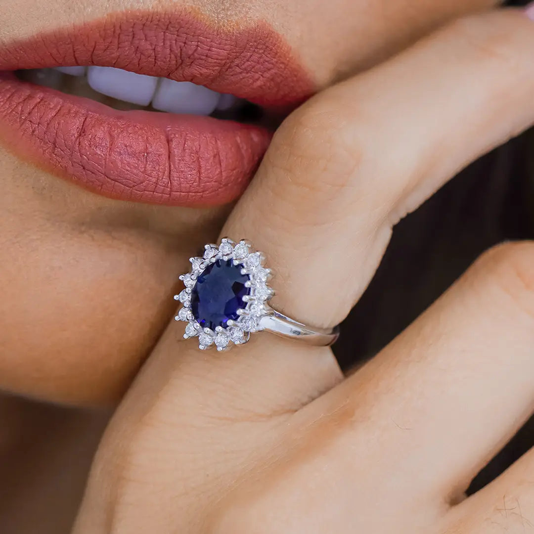 Mano de mujer con anillo en oro blanco de 18 quilates, zafiro en color azul en el centro y diamantes alrededor, hecho en Joyería Caracas. 