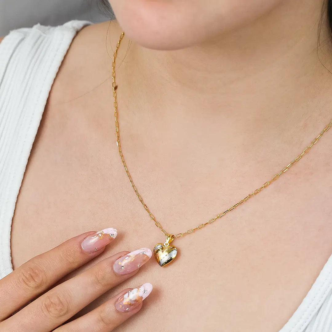 Cuello de mujer con cadena y dije en forma de corazón en oro amarillo, blanco y rosa de 18 quilates, hecho en Joyería Caracas. 