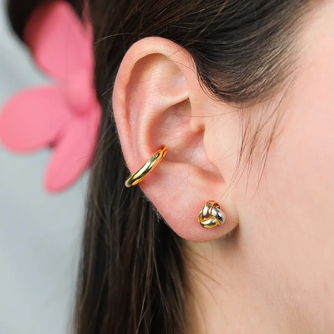 Oreja de mujer con topito en forma de nudo en oro amarillo, blanco y rosa de 18 quilates, hechos en Joyería Caracas. 