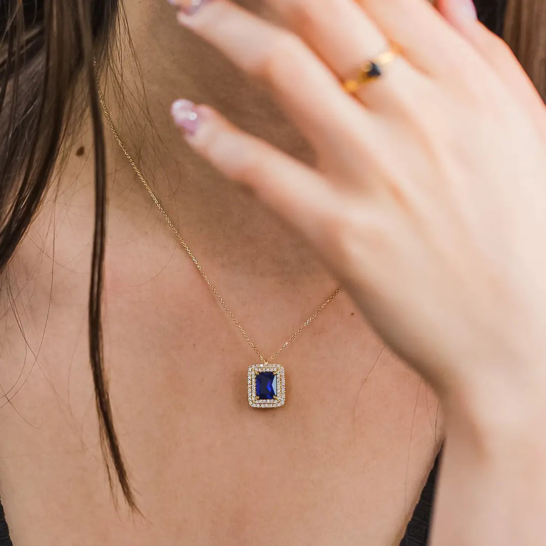 Cuello de mujer usando gargantilla con dije en oro amarillo de 18 quilates con cristal cuadrado de color azul en el centro con cristales de color blanco alrededor, hecho en Joyería Caracas.  