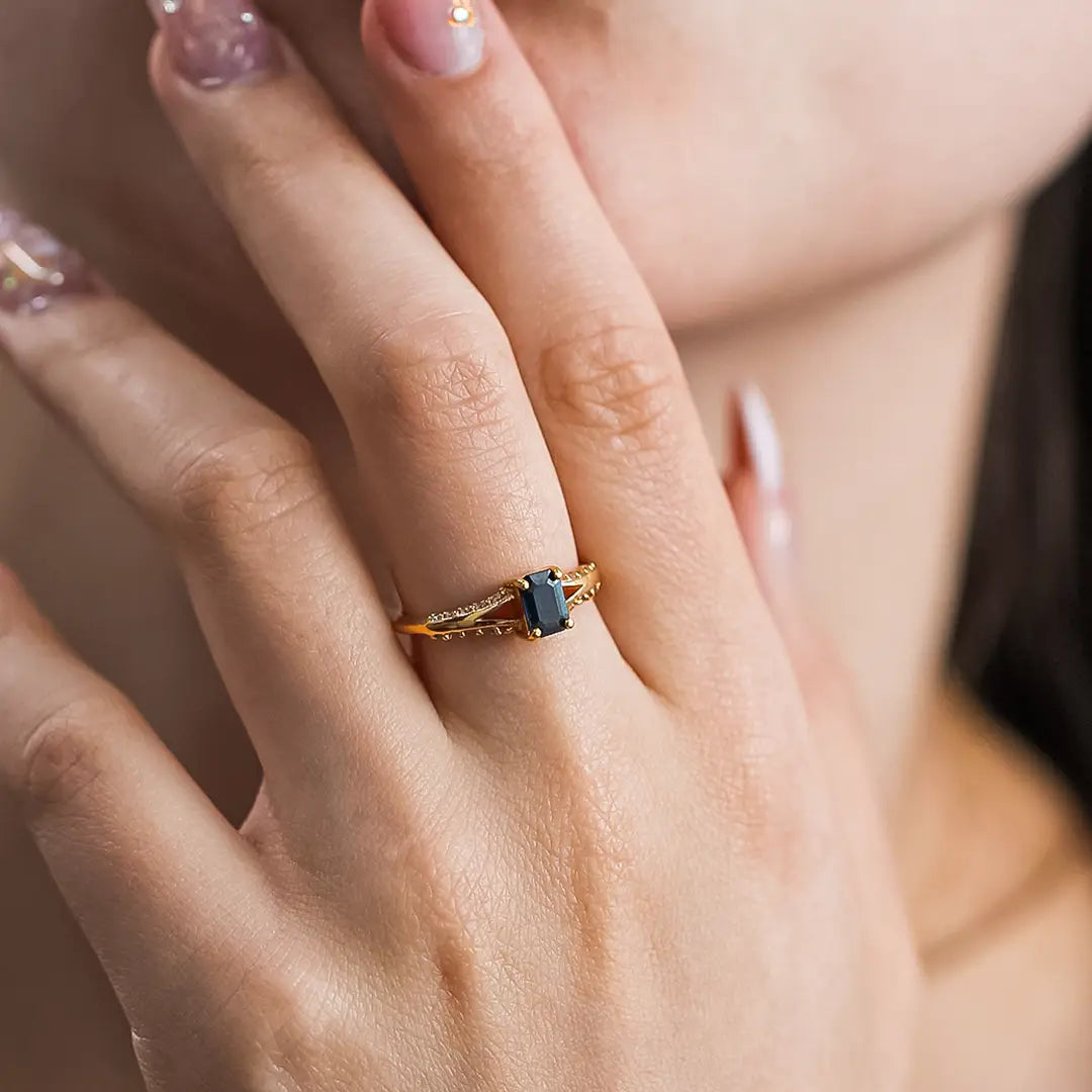 Mano de mujer con anillo en oro amarillo de 18 quilates con zafiro de color azul y 20 diamantes de color blanco, hecho en Joyería Caracas. 