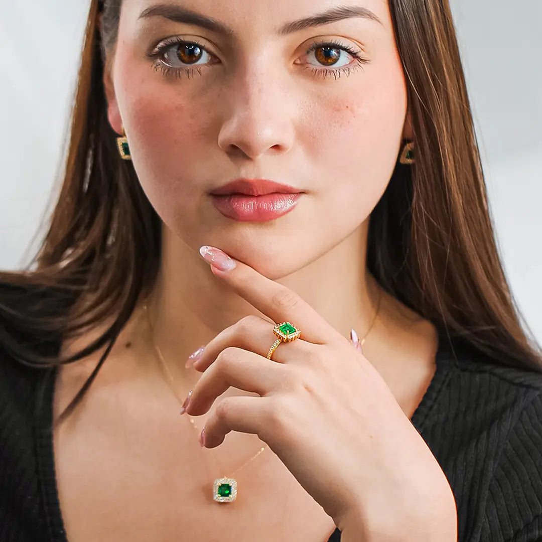 Mano de mujer con anillo en oro amarillo de 18 quilates con esmeralda y diamantes, hecho en Joyería Caracas. 