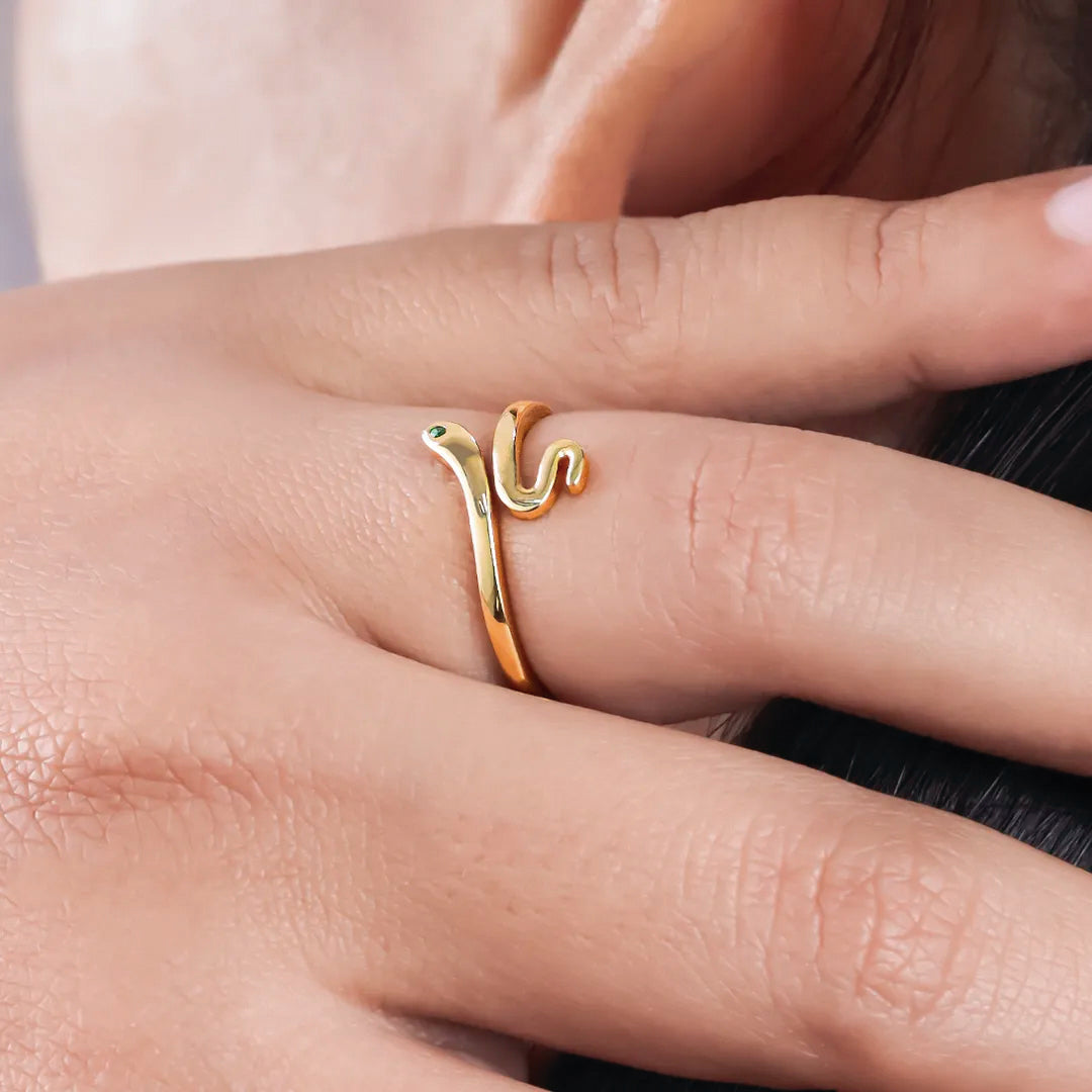 Mano de mujer con anillo en forma de serpiente en oro amarillo de 18 quilates con cristal de color verde, hecho en Joyería Caracas. 