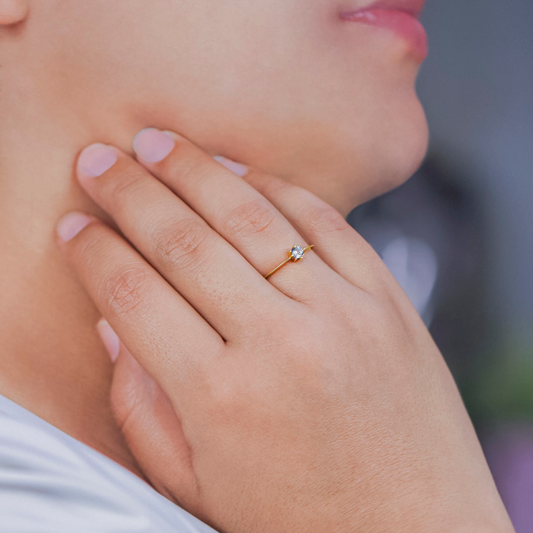 Mano de mujer con anillo en oro amarillo de 18 quilates con cristal de color blanco, hecho en Joyería Caracas. 