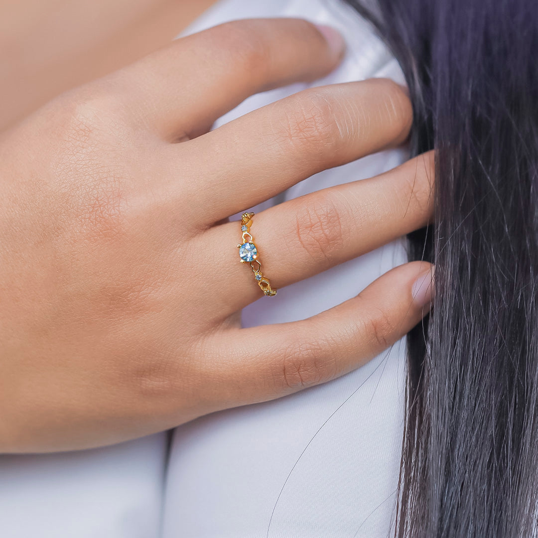 Mano de mujer con anillo en oro amarillo de 18 quilates con cristal de color blanco en el centro y cristales de color blanco, hecho en Joyería Caracas. 