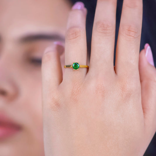 Mano de mujer con anillo en oro amarillo de 18 quilates con cristal de color verde, hecho en Joyería Caracas. 
