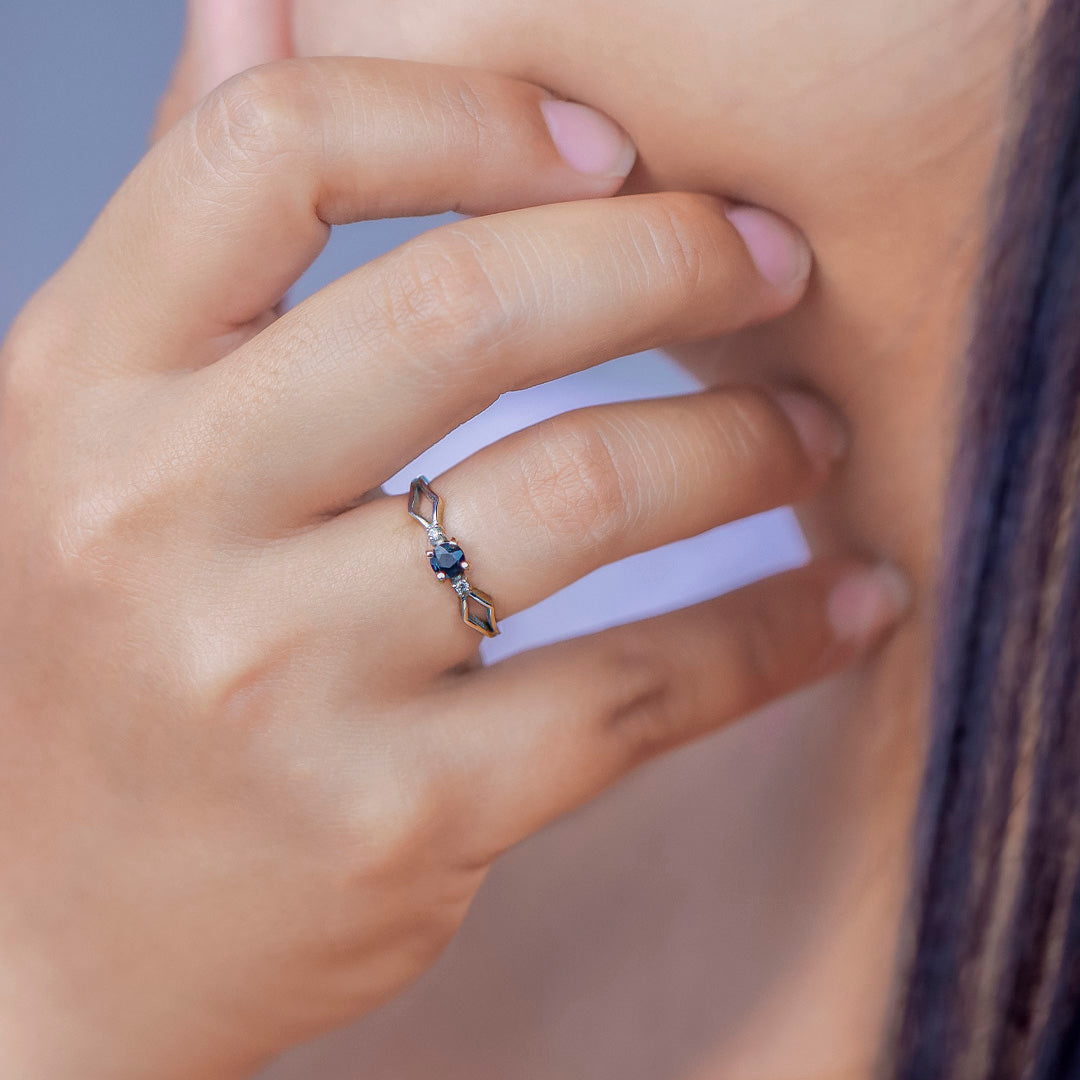 Mano de mujer con anillo en oro blanco de 18 quilates con zafiro de color azul en el centro y 2 cristales de color blanco alrededor, hecho en Joyería Caracas. 