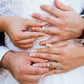 Manos de hombre y mujer en matrimonio sosteniendo cada argolla en oro amarillo de 18k, la cual tiene texturas que lucen cada argolla, hechas en Joyería Caracas. 