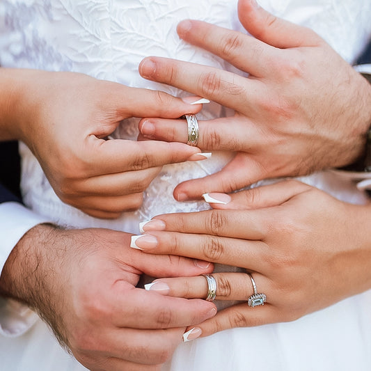Manos de hombre y mujer en matrimonio sosteniendo cada argolla en oro amarillo de 18k, la cual tiene texturas que lucen cada argolla, hechas en Joyería Caracas. 