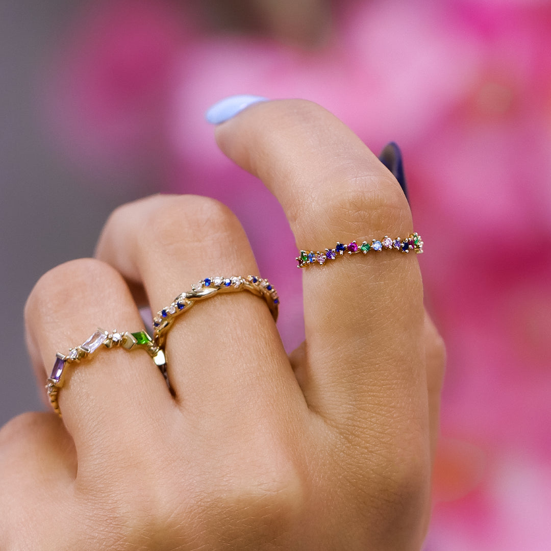 Mano de mujer con anillo asimétrico en oro amarillo de 18 quilates y cristales de distintos colores, hecho en Joyería Caracas. 